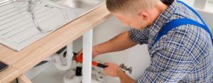 plumber working on a sink pipe