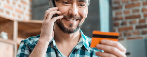 man talking on cell phone and looking at debit card