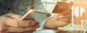 man holding cell phone and debit card